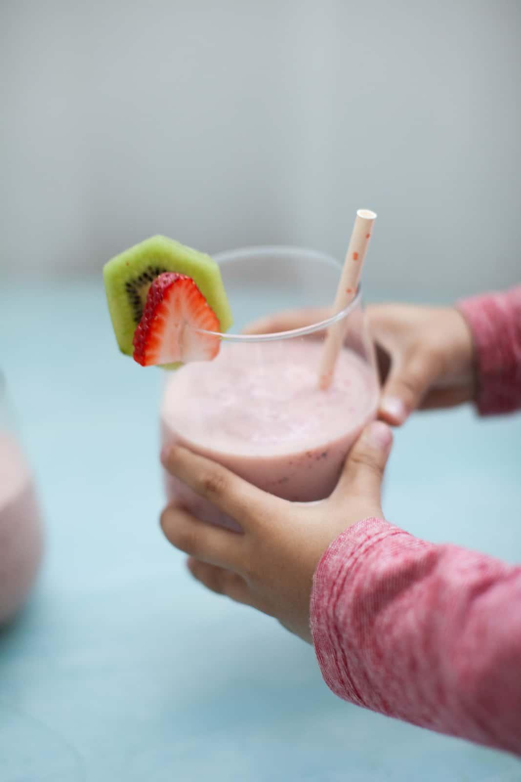 Person enjoying a strawberry kiwi smoothie outdoors
