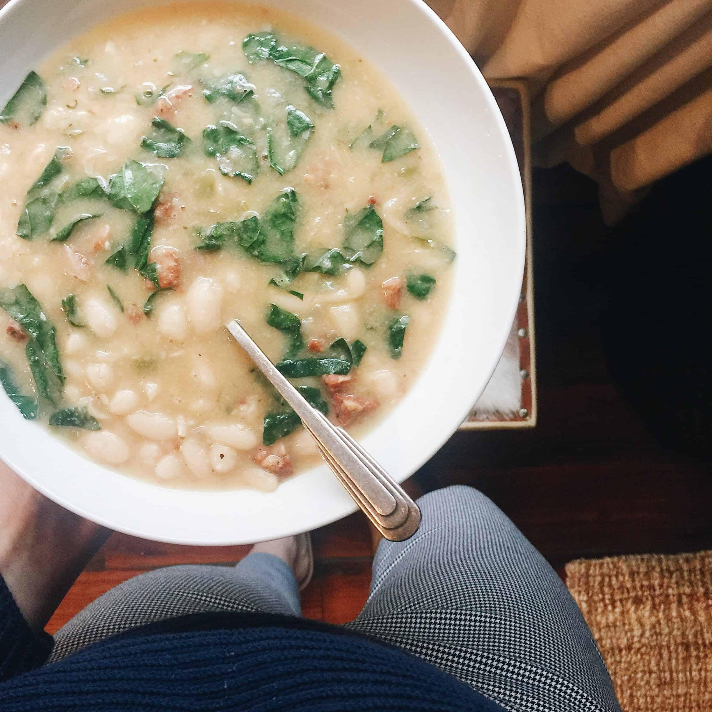 A person enjoying a bowl of kale and white bean soup
