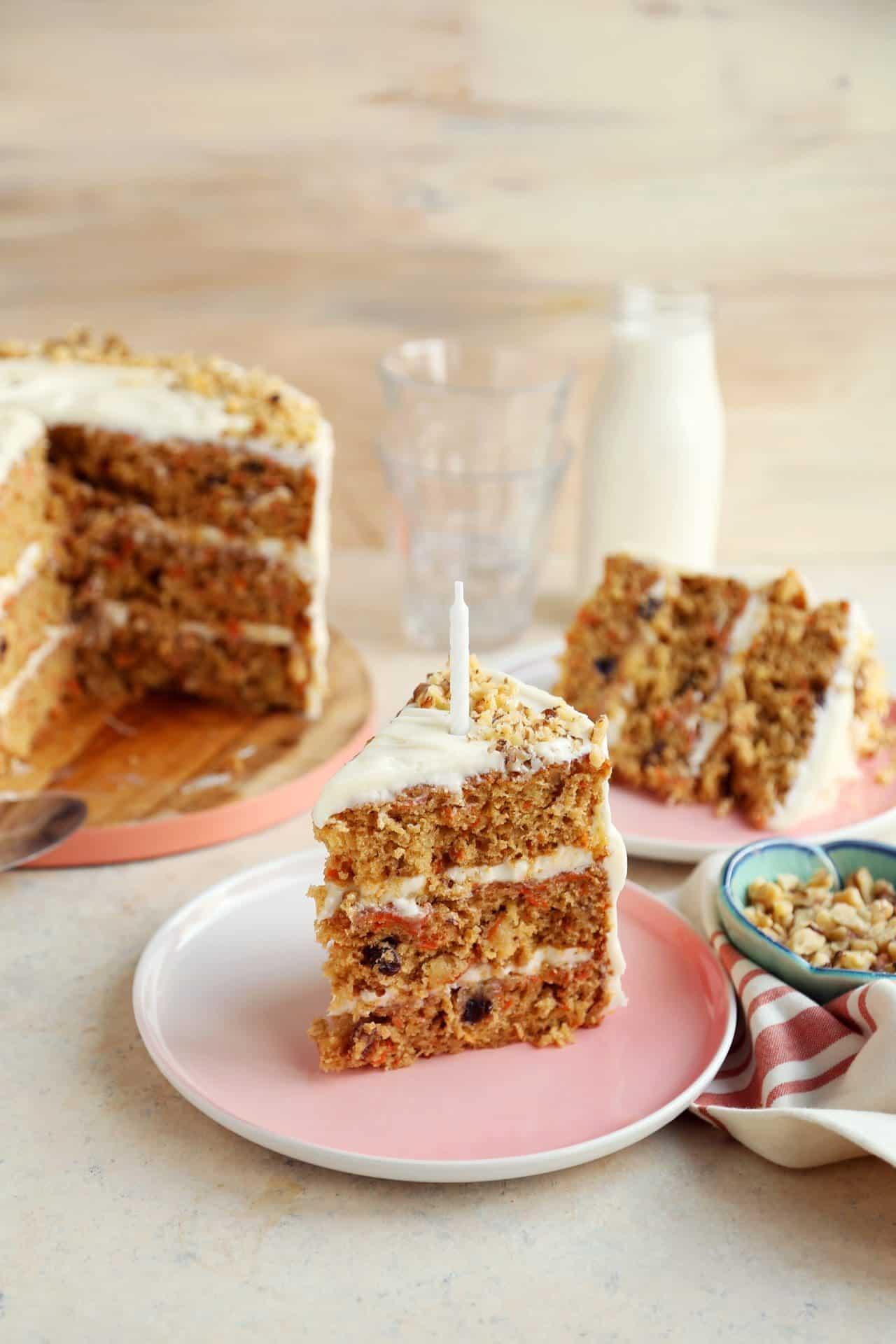 A whole carrot cake on a cake stand, surrounded by friends and family