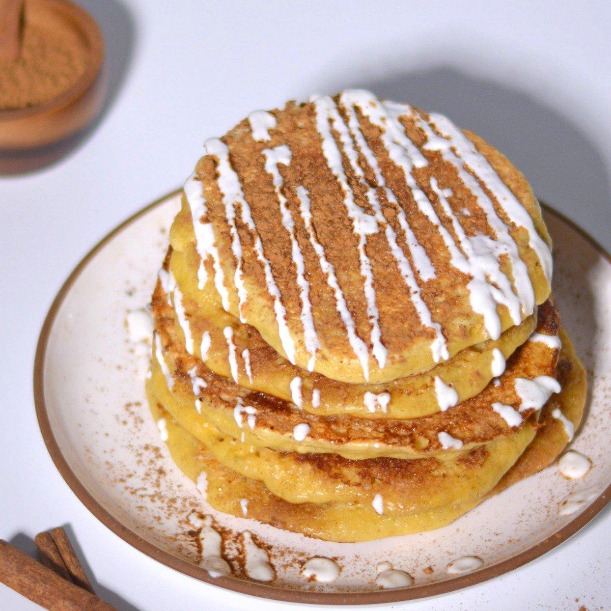 A stack of fluffy cinnamon sugar pancakes drizzled with maple syrup, dusted with extra cinnamon sugar