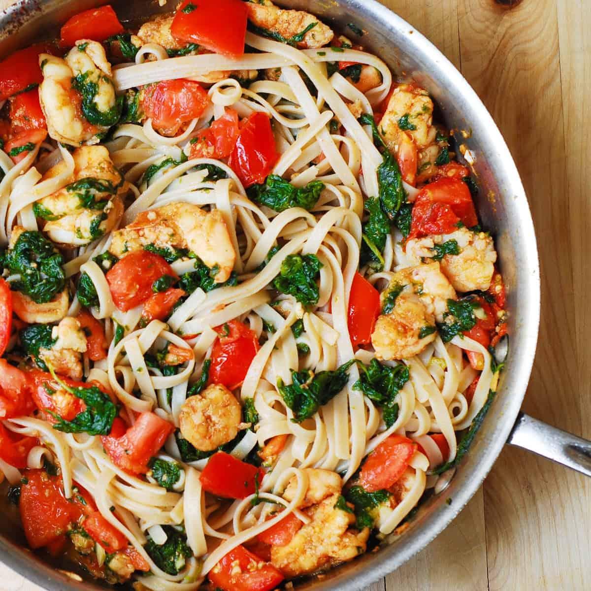 A close-up shot of the Garlic Shrimp & Spinach Salsa Pasta, highlighting the fresh ingredients and vibrant colors