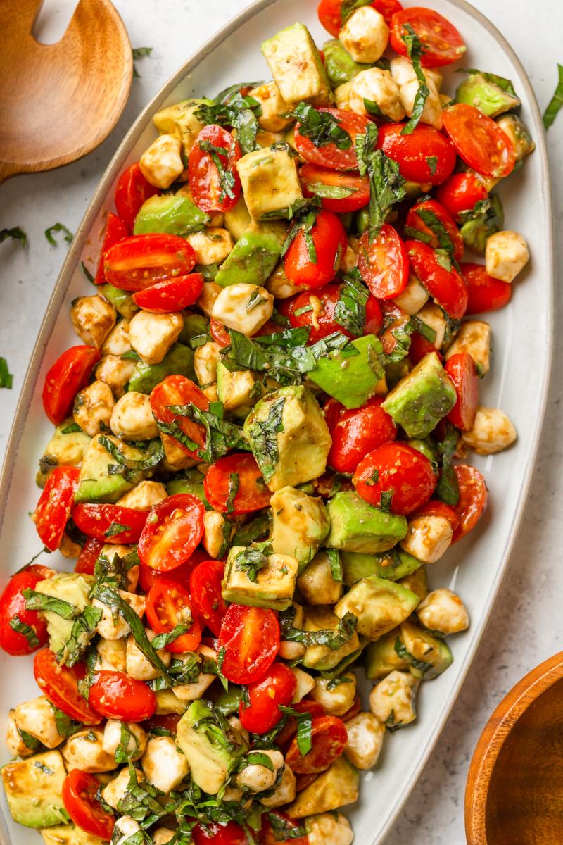 close-up shot of basil-infused avocado oil drizzled over a caprese salad