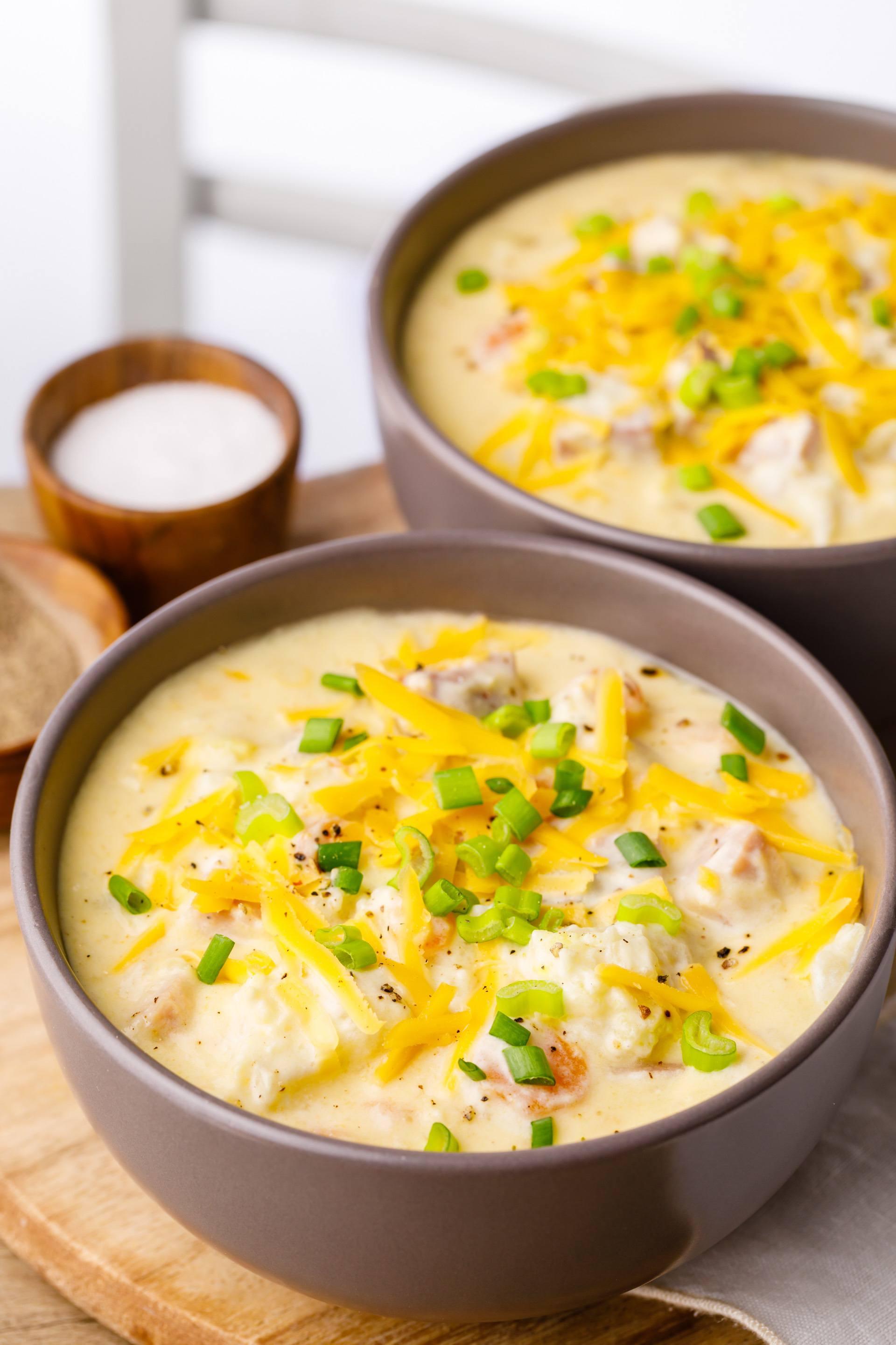Overhead shot of a steaming pot of Keto Hamster Soup with ingredients like ham, cauliflower rice, and vegetables scattered around