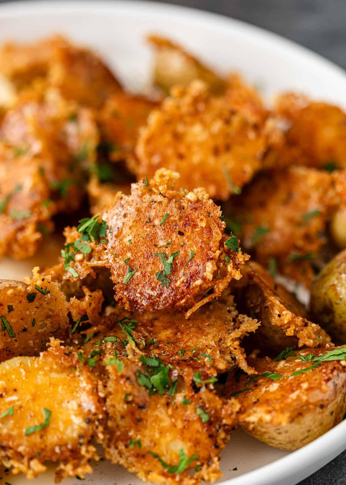 Close-up of perfectly crispy parmesan roasted potatoes with fresh herbs, golden brown
