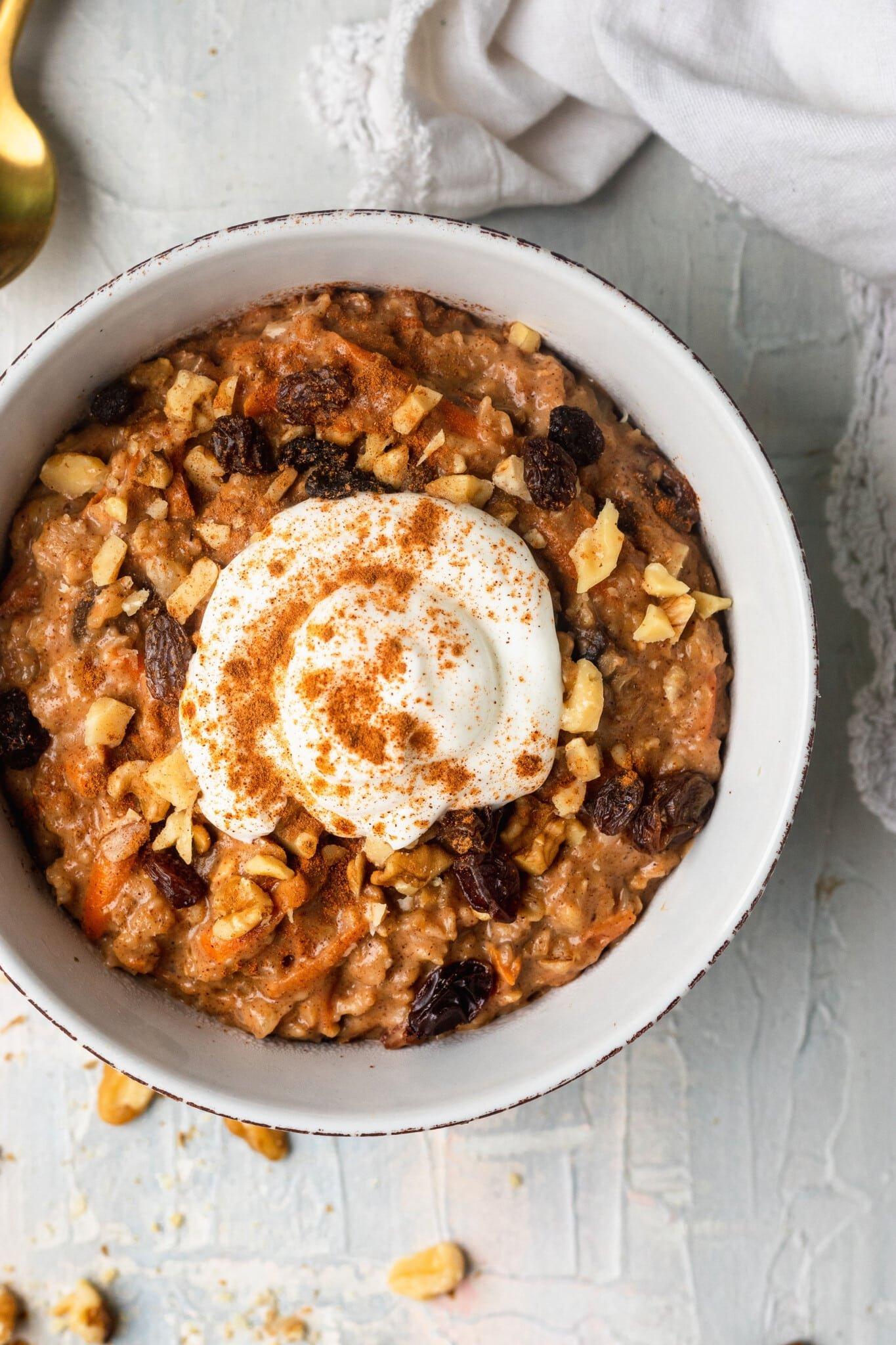 A warm bowl of carrot cake oatmeal, garnished with chopped pecans and a sprinkle of cinnamon