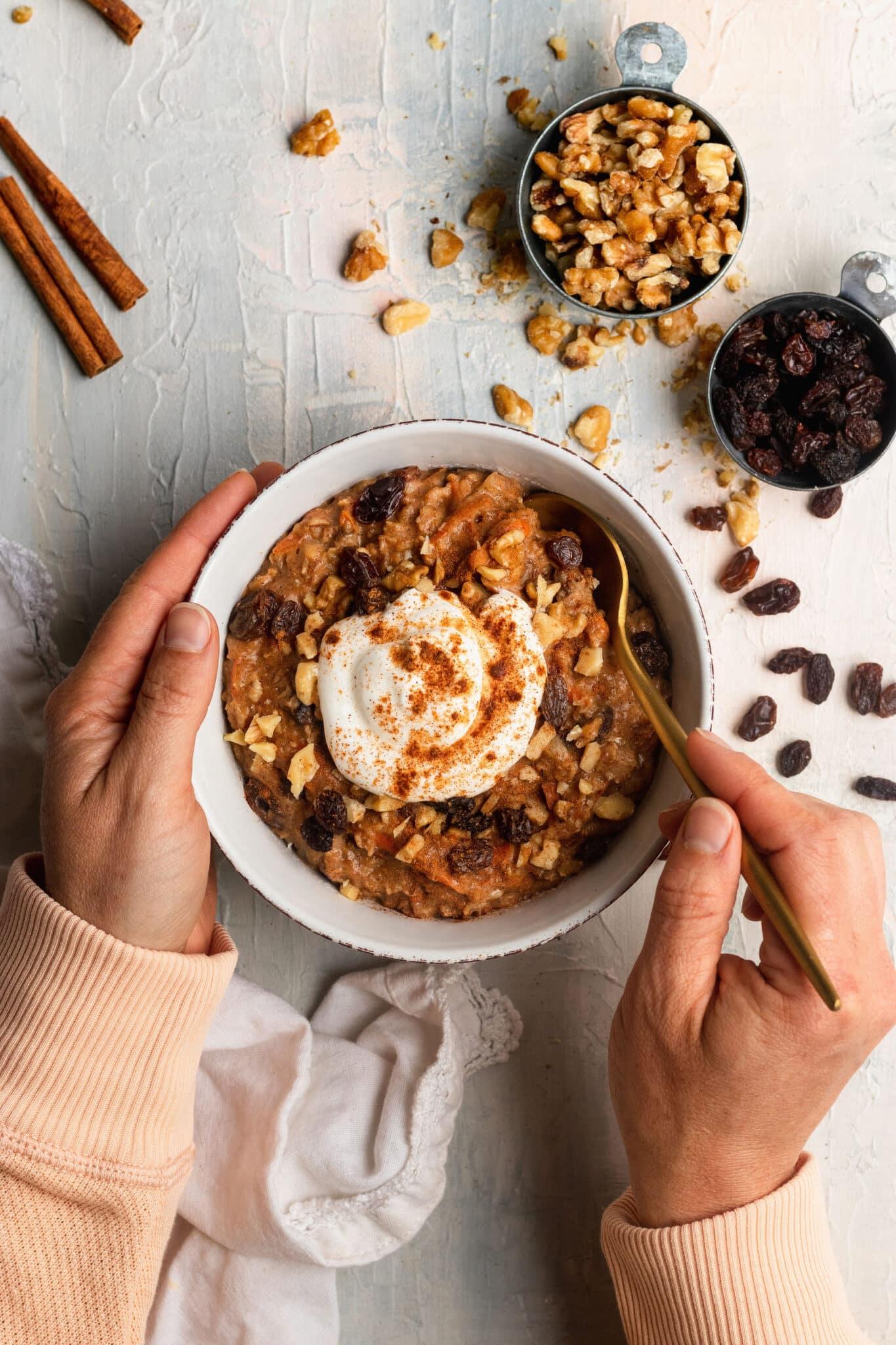 A person enjoying a bowl of carrot cake oatmeal in a cozy setting