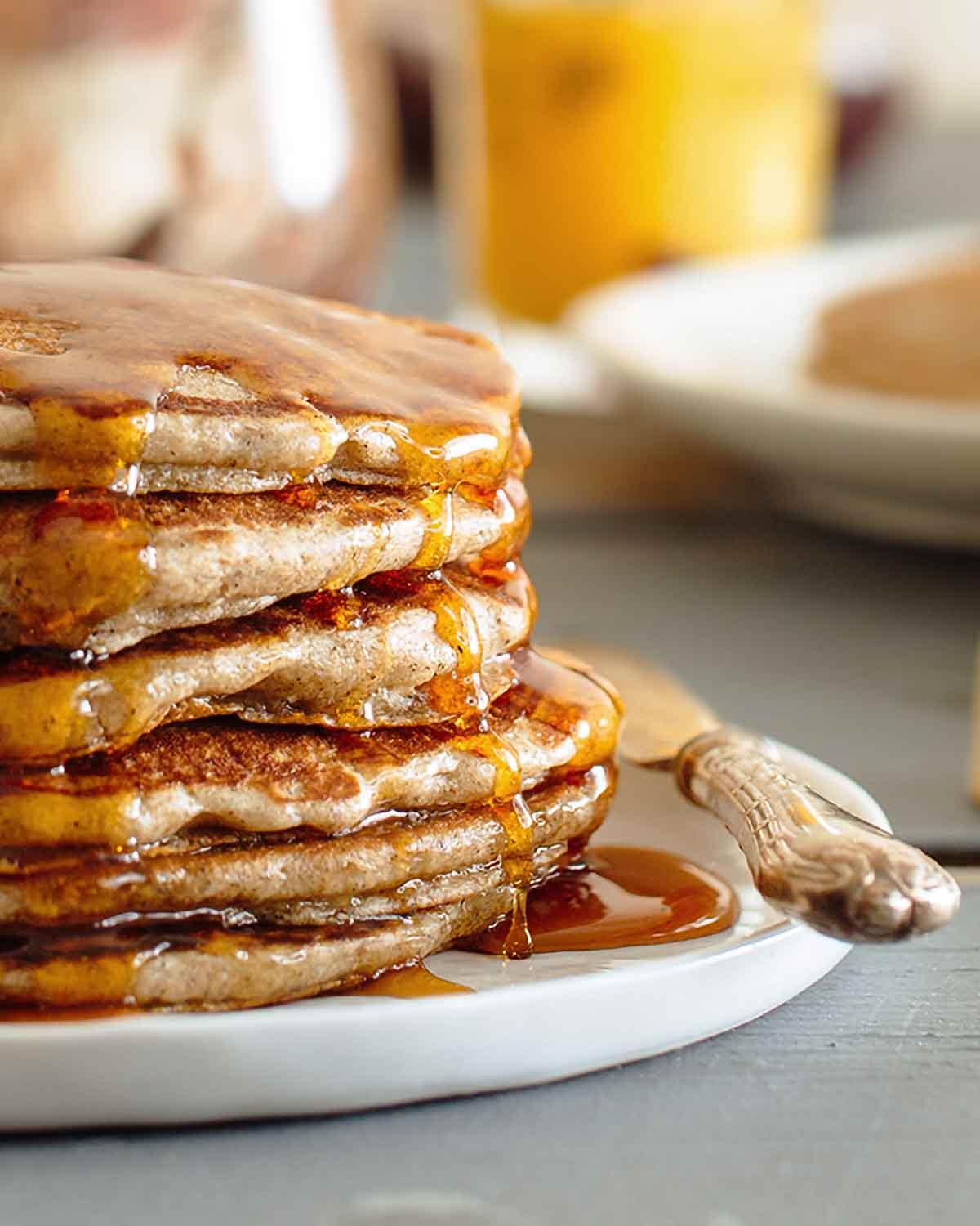 overhead shot of a stack of buckwheat pancakes being drizzled with maple syrup