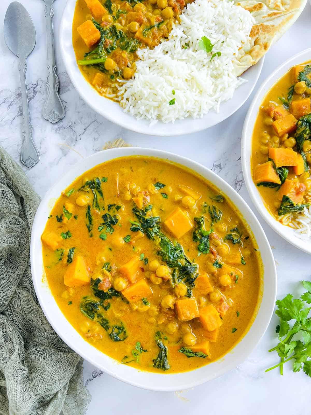 A close-up shot highlighting the texture and colors of the sweet potato and chickpea curry, emphasizing the creamy coconut milk and vibrant spices.