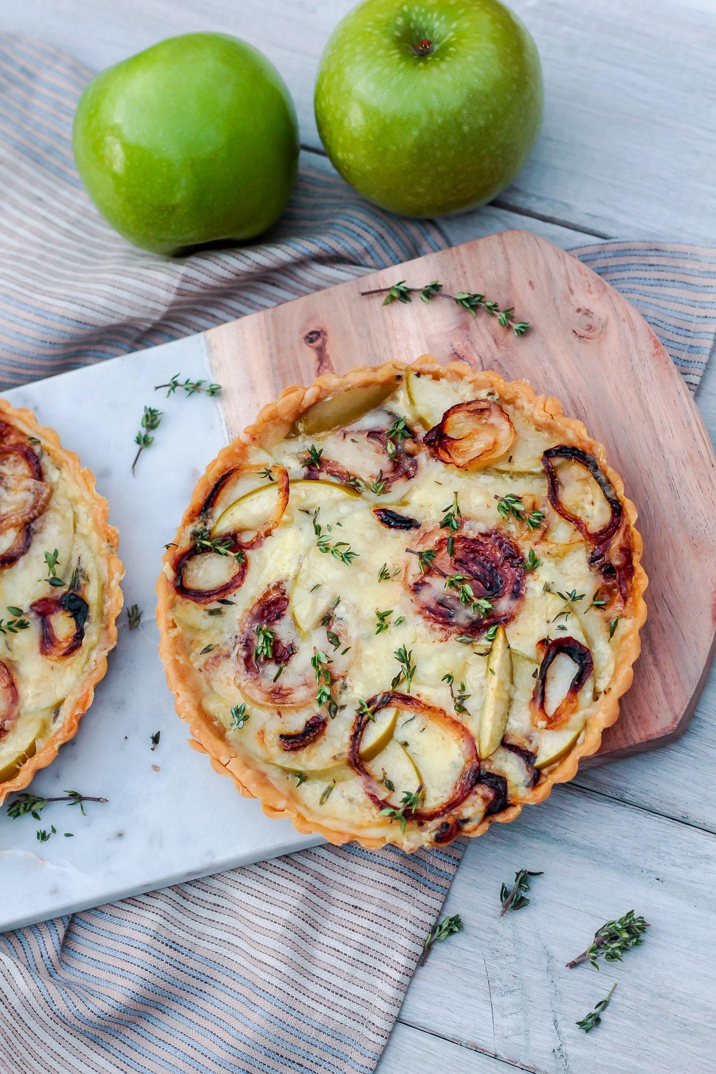 A beautifully arranged apple and gruyere tart on a serving platter