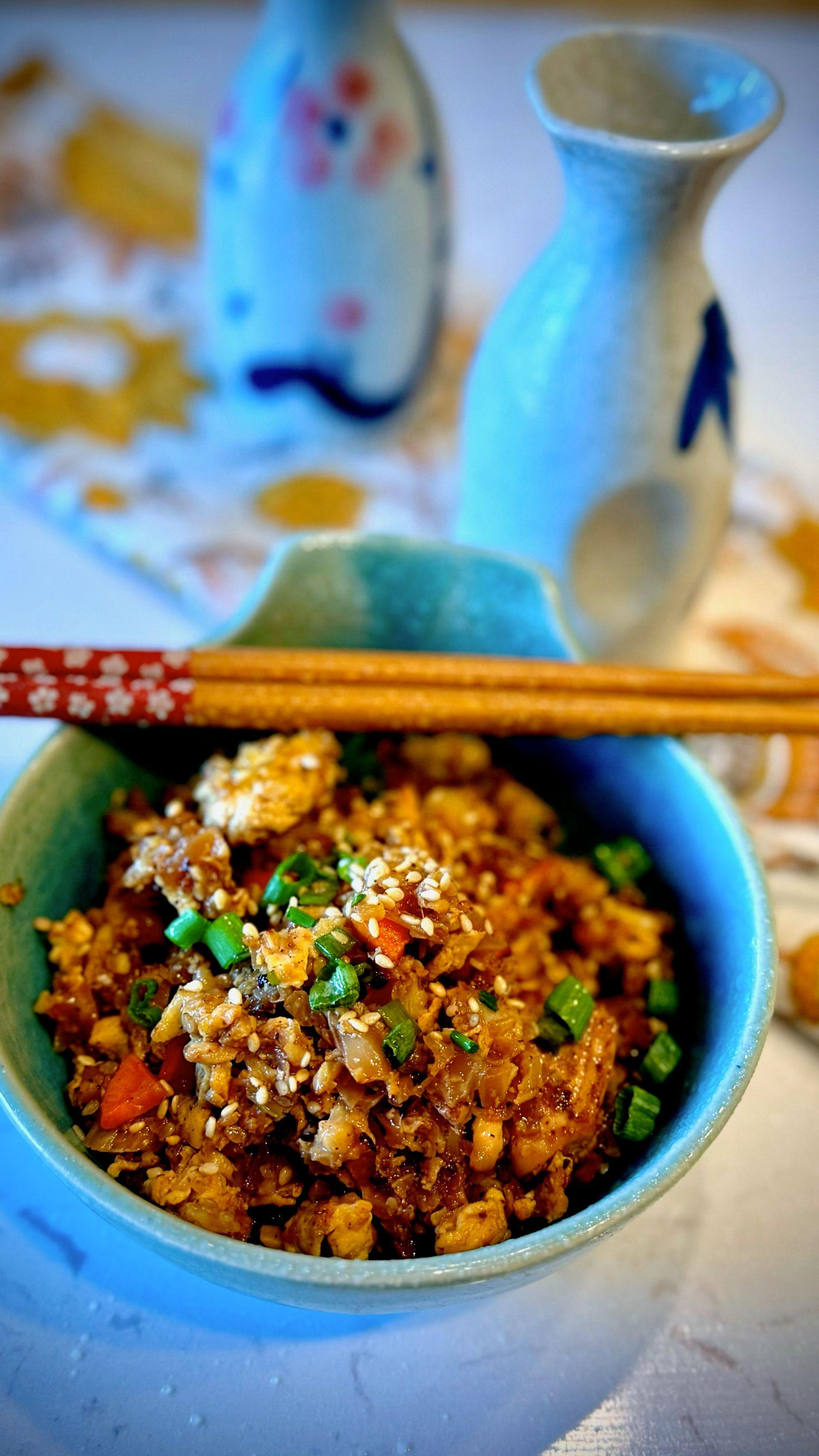 A vibrant and appetizing bowl of cauliflower fried rice, garnished with sesame seeds and green onions