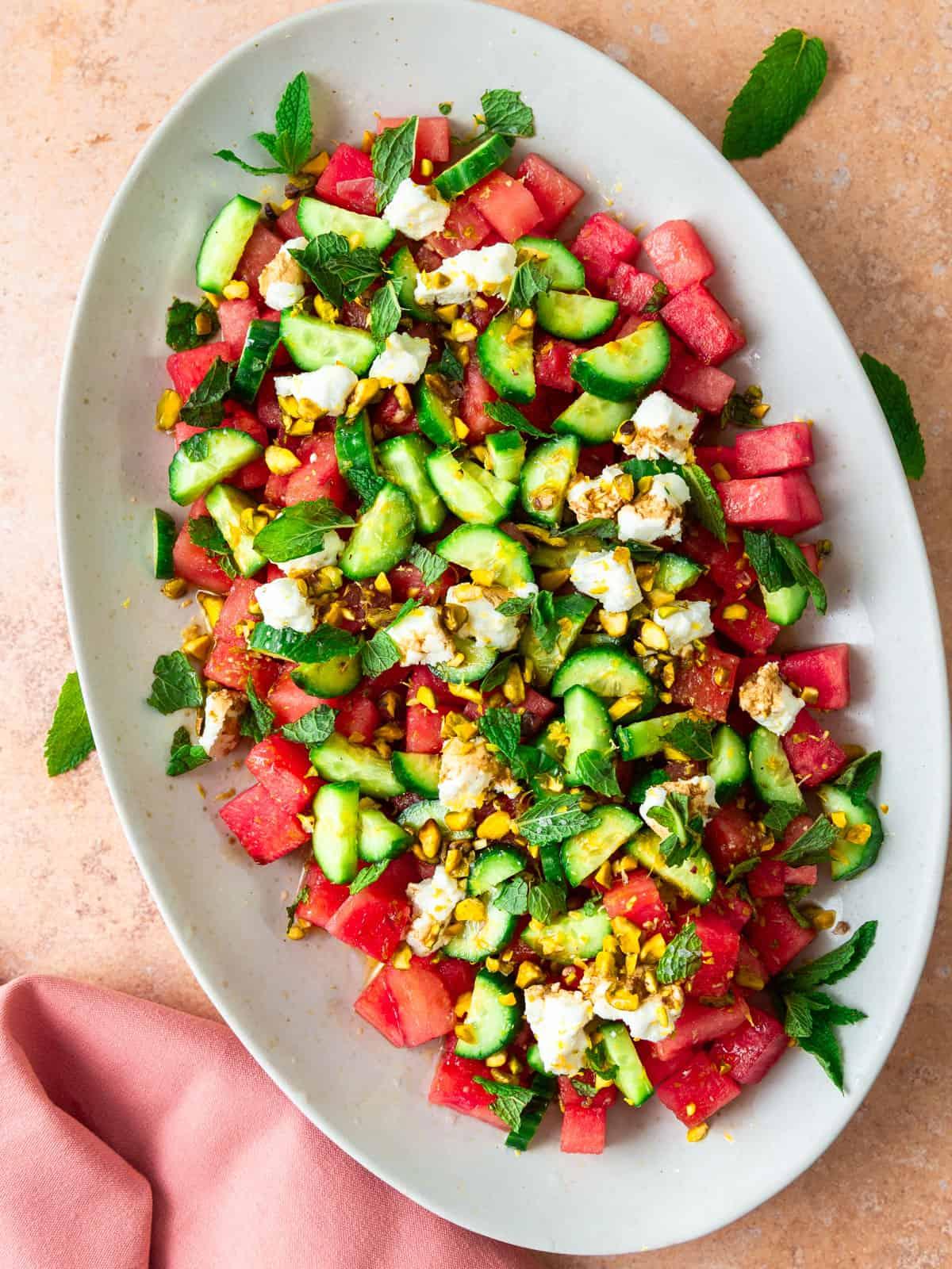 A vibrant summer salad with juicy watermelon chunks, creamy goat cheese, fresh mint, and a balsamic glaze drizzled over the top