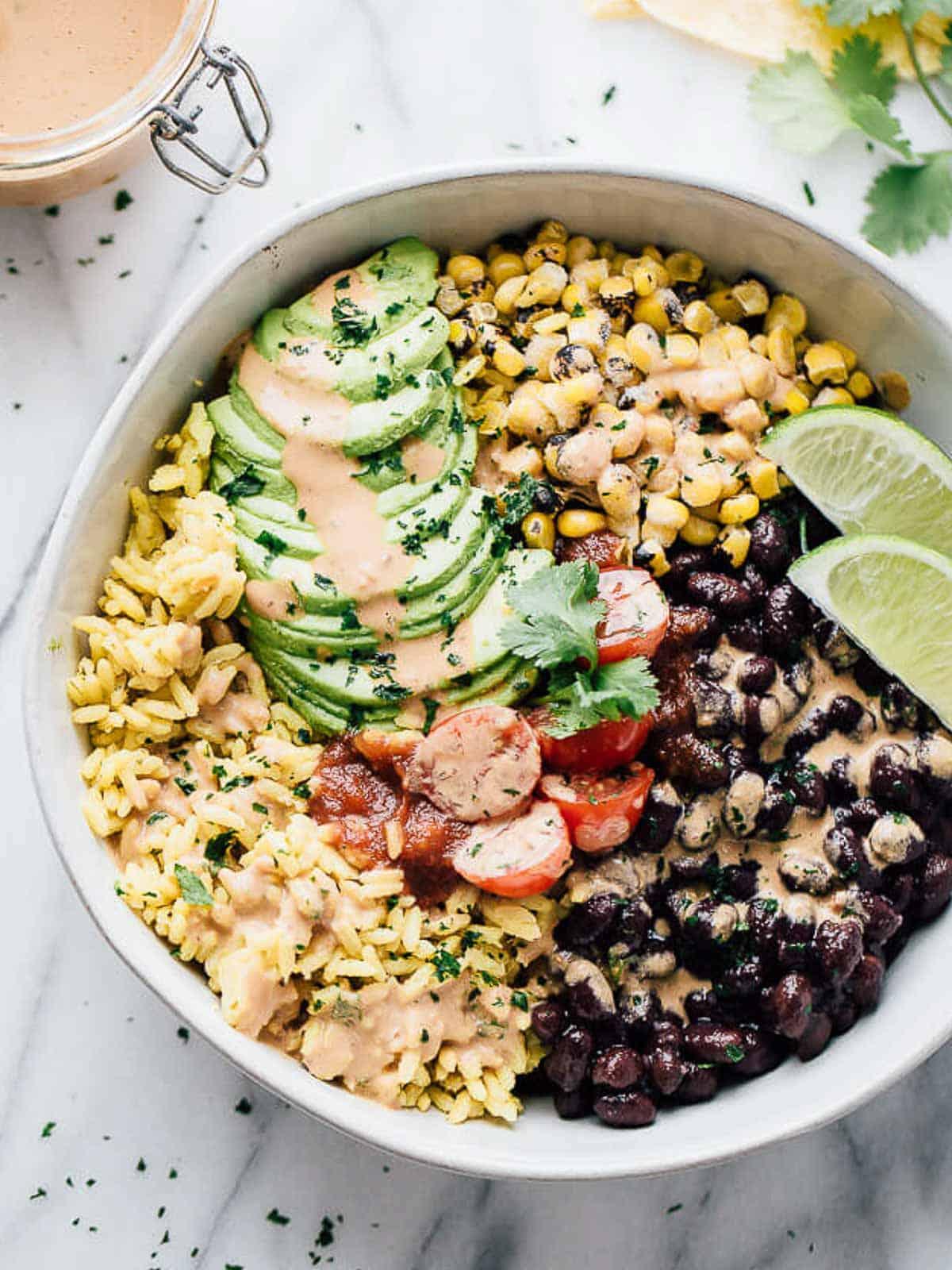 person assembling a black bean burrito bowl