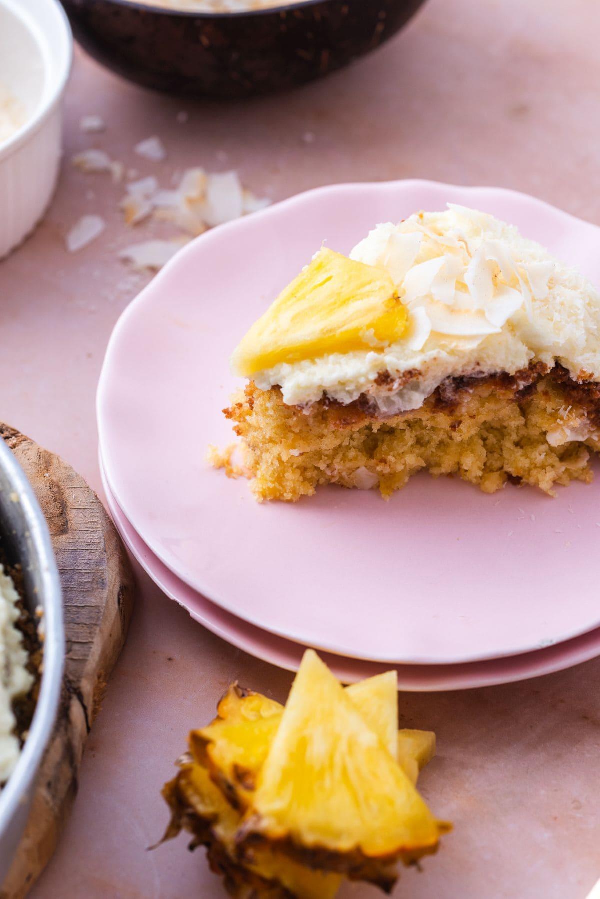 A golden-brown pineapple upside-down cake with a fluffy coconut cream frosting, garnished with toasted coconut flakes and a pineapple wedge.
