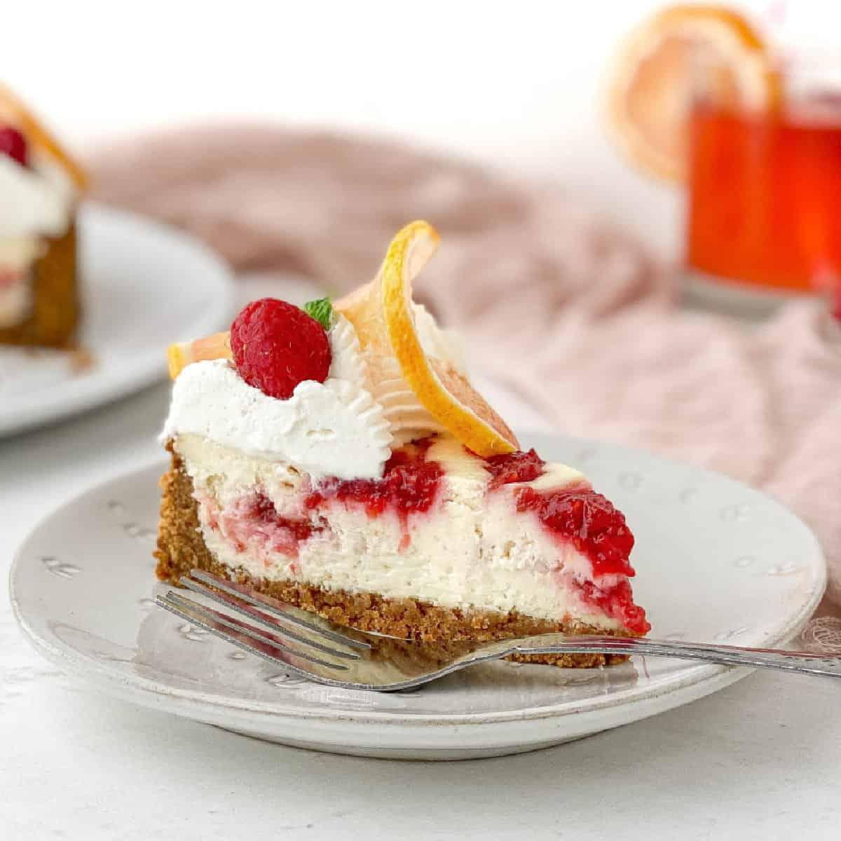 Close-up shot of a slice of Lemon & Raspberry Cheesecake, showing the creamy texture and juicy raspberries.