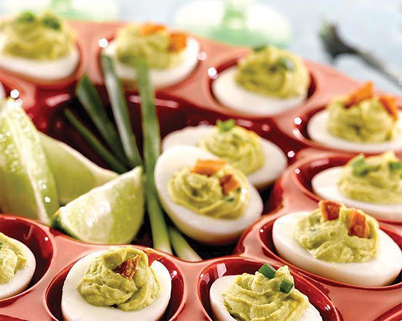 A rustic wooden table with various ingredients for making Avocado Ranch Deviled Eggs