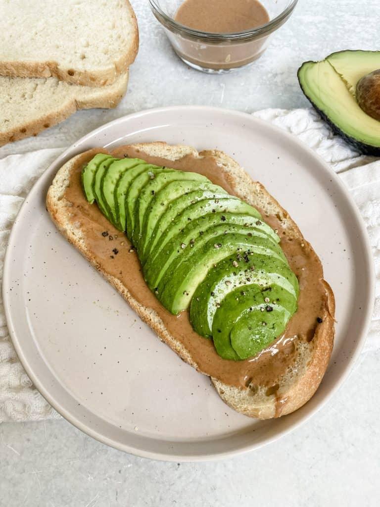 A slice of perfectly toasted bread topped with creamy avocado and a swirl of peanut butter