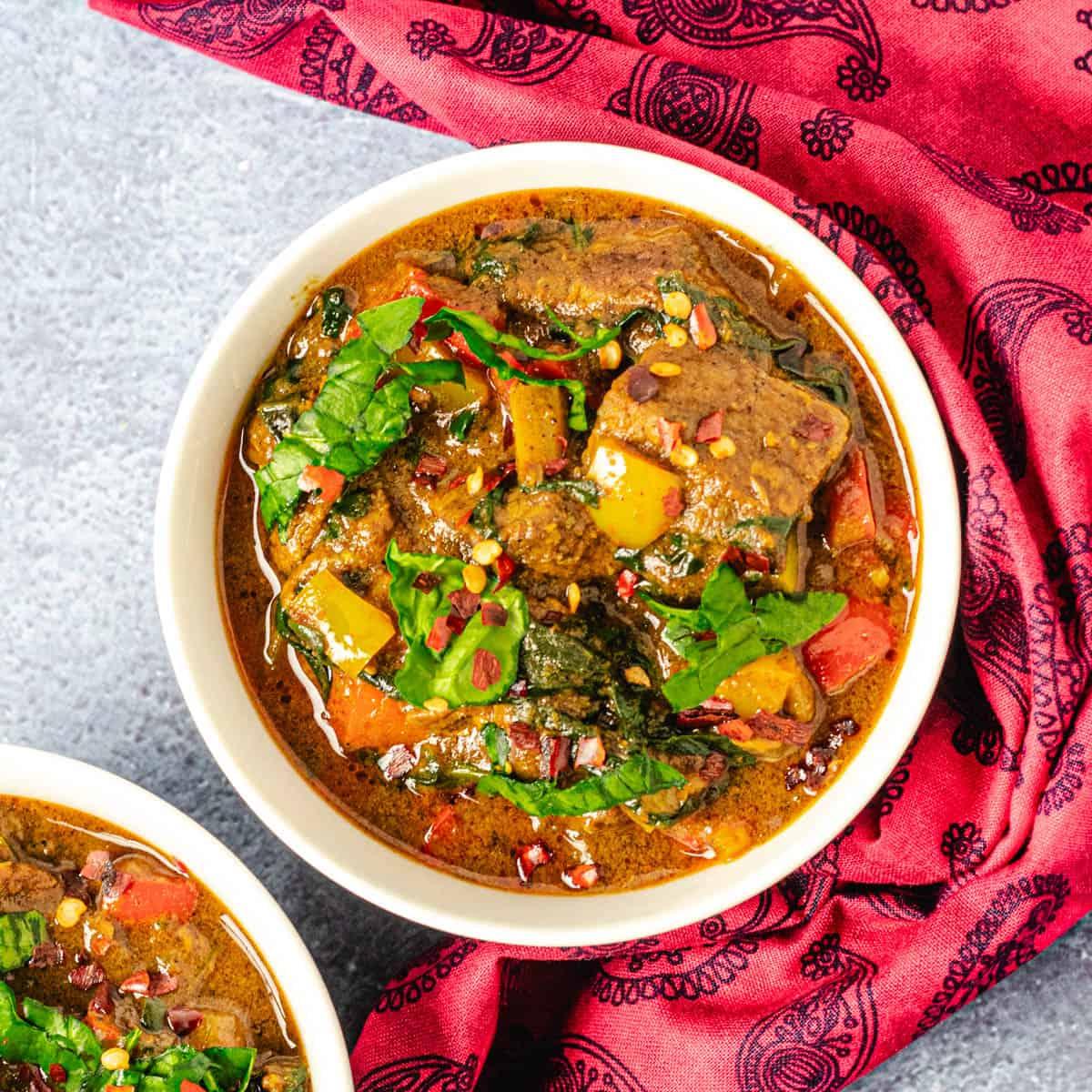 overhead shot of lamb curry with coconut milk and spinach in a dutch oven