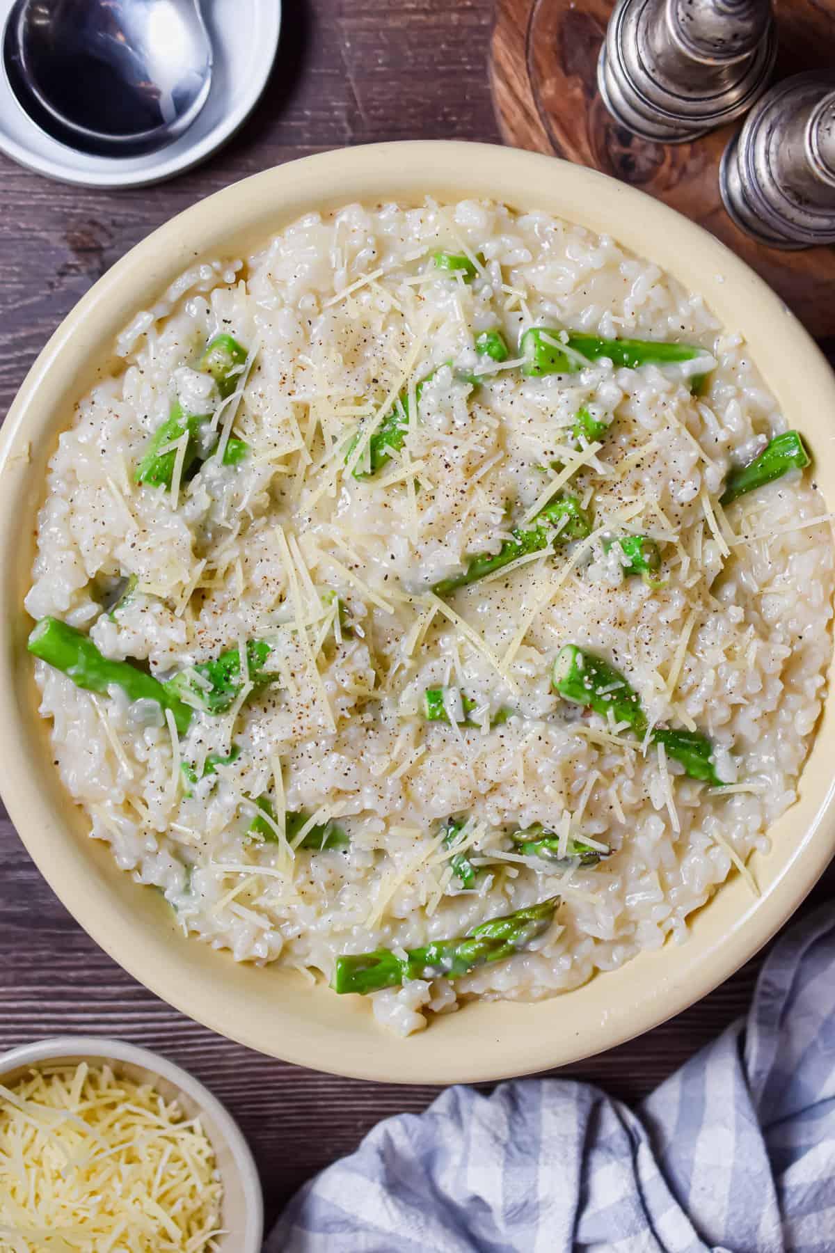 A person stirring a pot of asparagus risotto, showing the creamy texture.