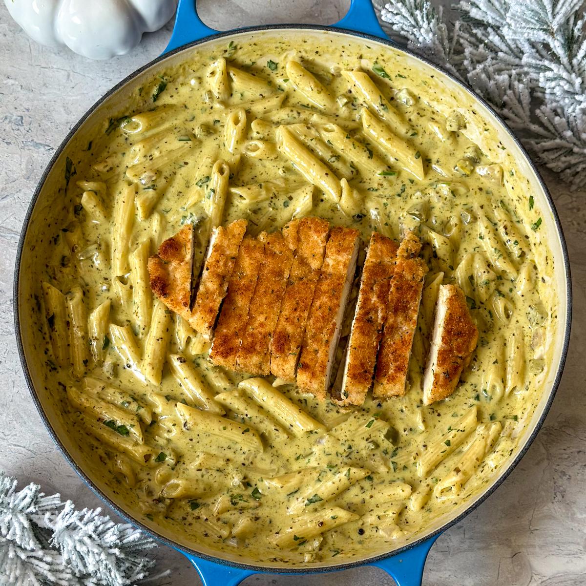 A person tossing creamy pesto pasta in a pan