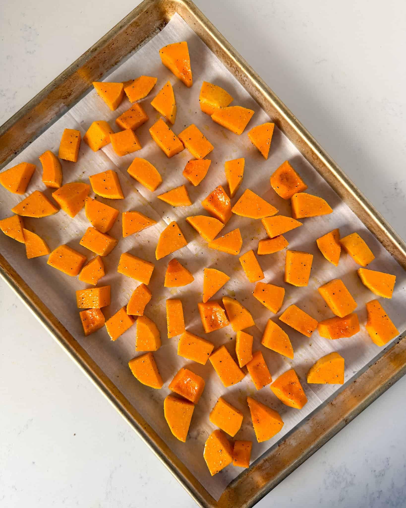 close-up shot of golden brown butternut squash peel and seed brittle on a parchment-lined baking sheet