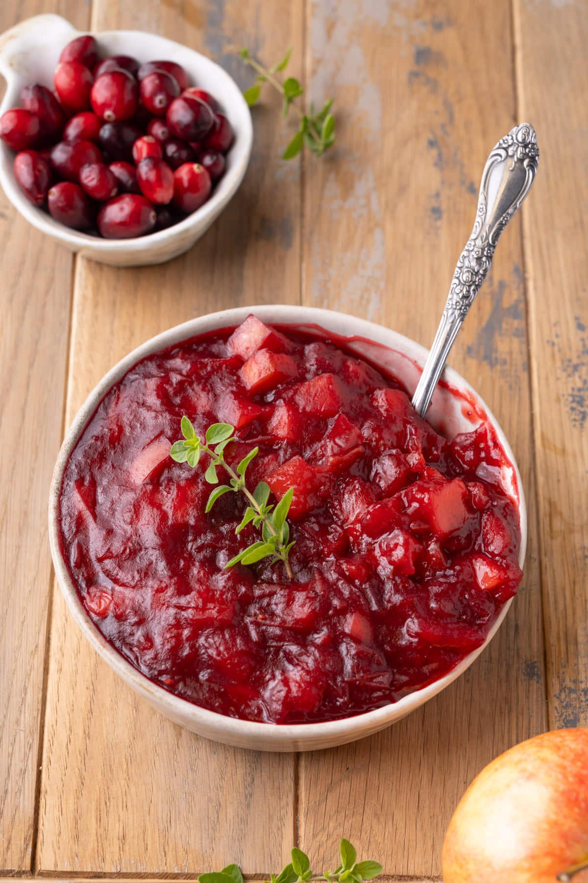 Rustic table setting with a bowl of homemade cranberry apple sauce as centerpiece, soft lighting