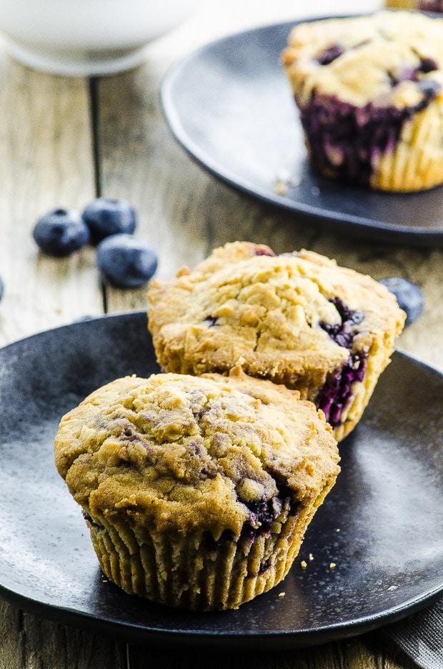 A plate of coconut yogurt blueberry muffins, garnished with fresh blueberries