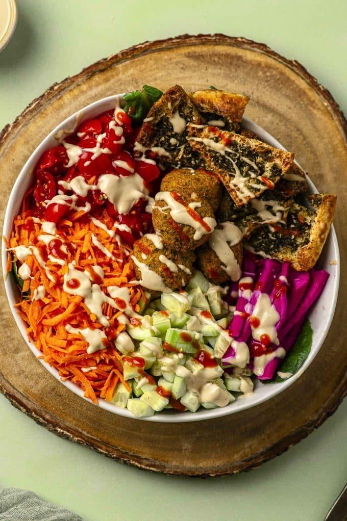 Close up shot of a bowl of falafel and olive salad with a side of pita bread