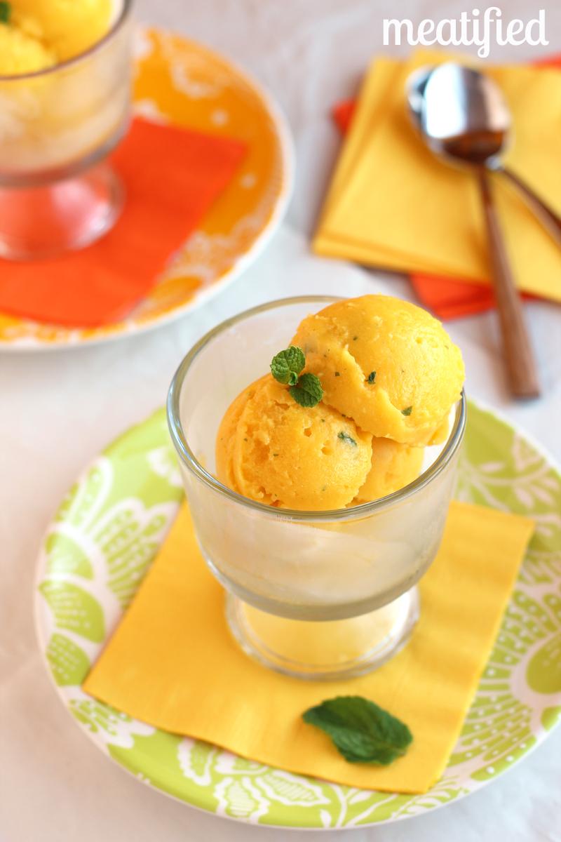 Close-up shot of a vibrant mango sorbet with fresh mint leaves garnish