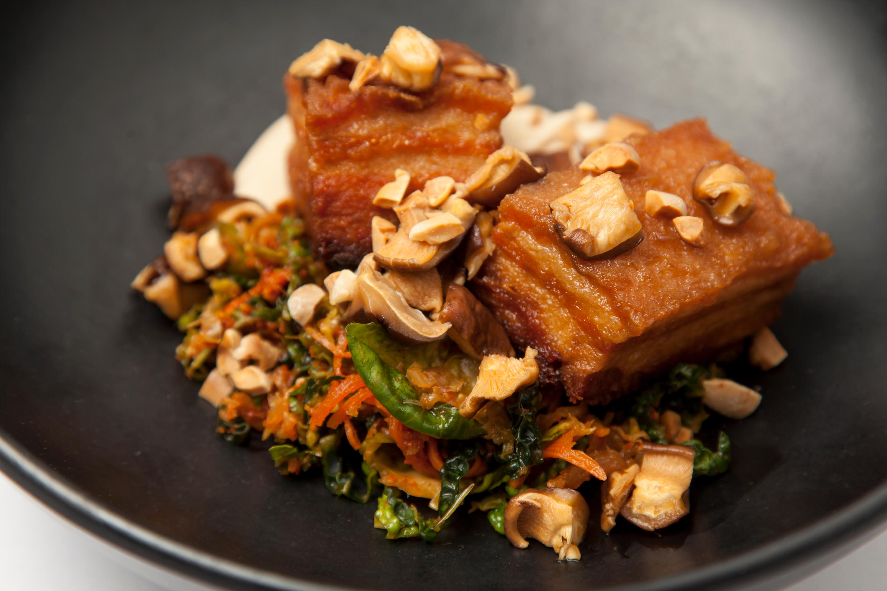 A table set for a dinner party with a platter of kimchi-butter glazed pork belly as the centerpiece