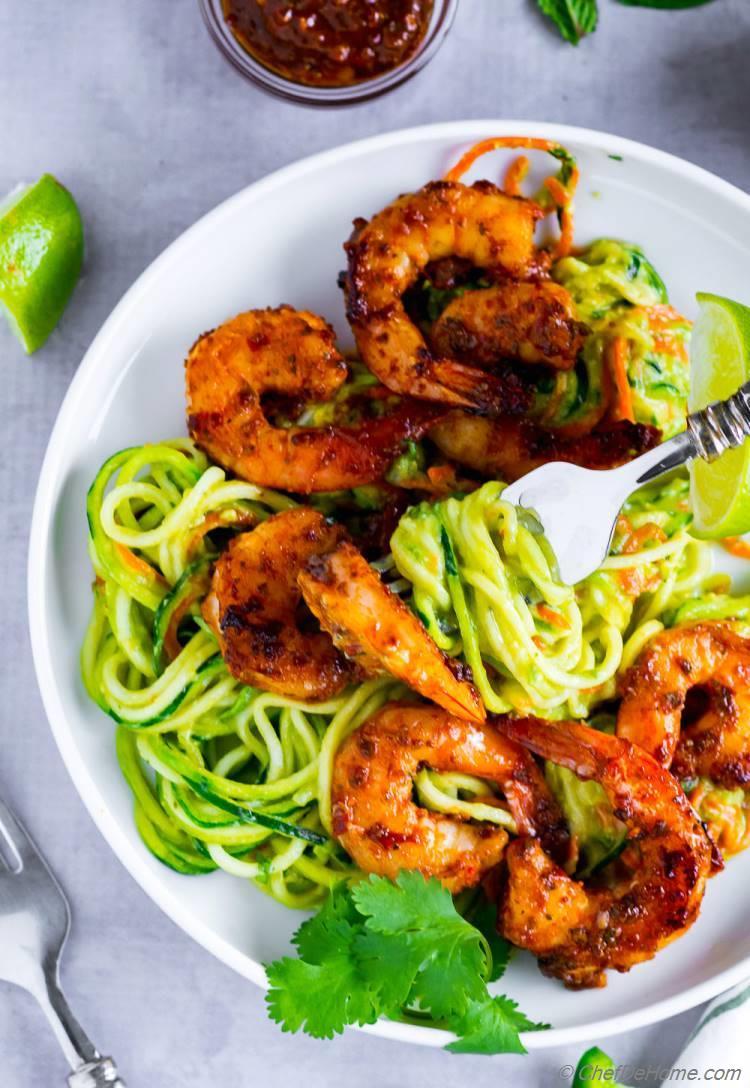 A colorful plate of zoodles with creamy avocado and shrimp