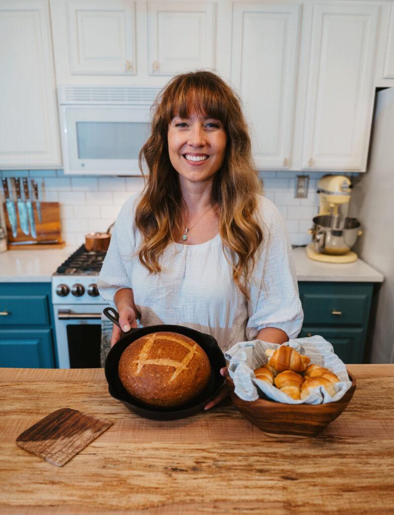 woman smiling holding loaf of freshly baked chocolate sourdough bread