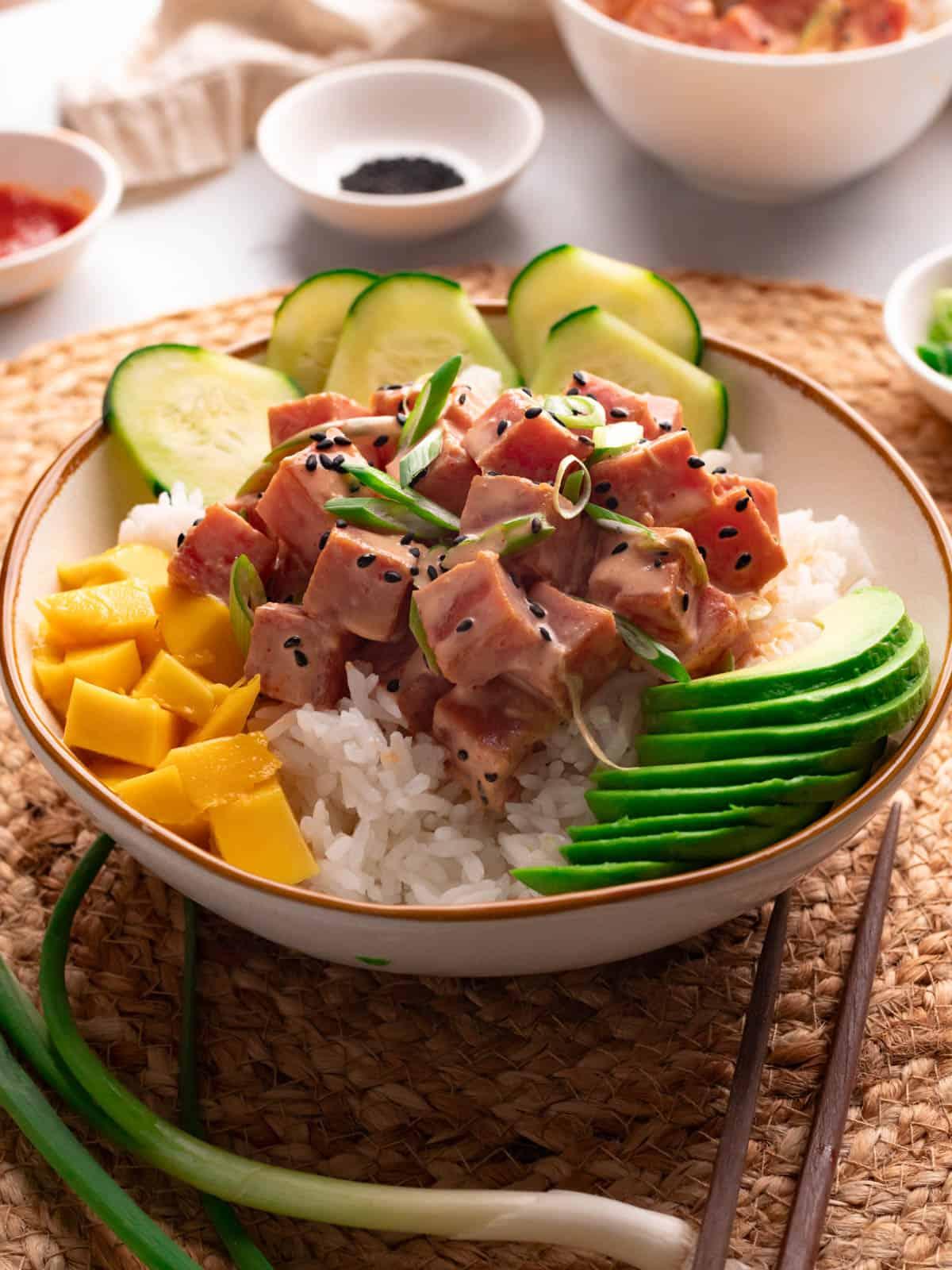 A bowl of spicy tuna dip with various garnishes such as green onions and sesame seeds