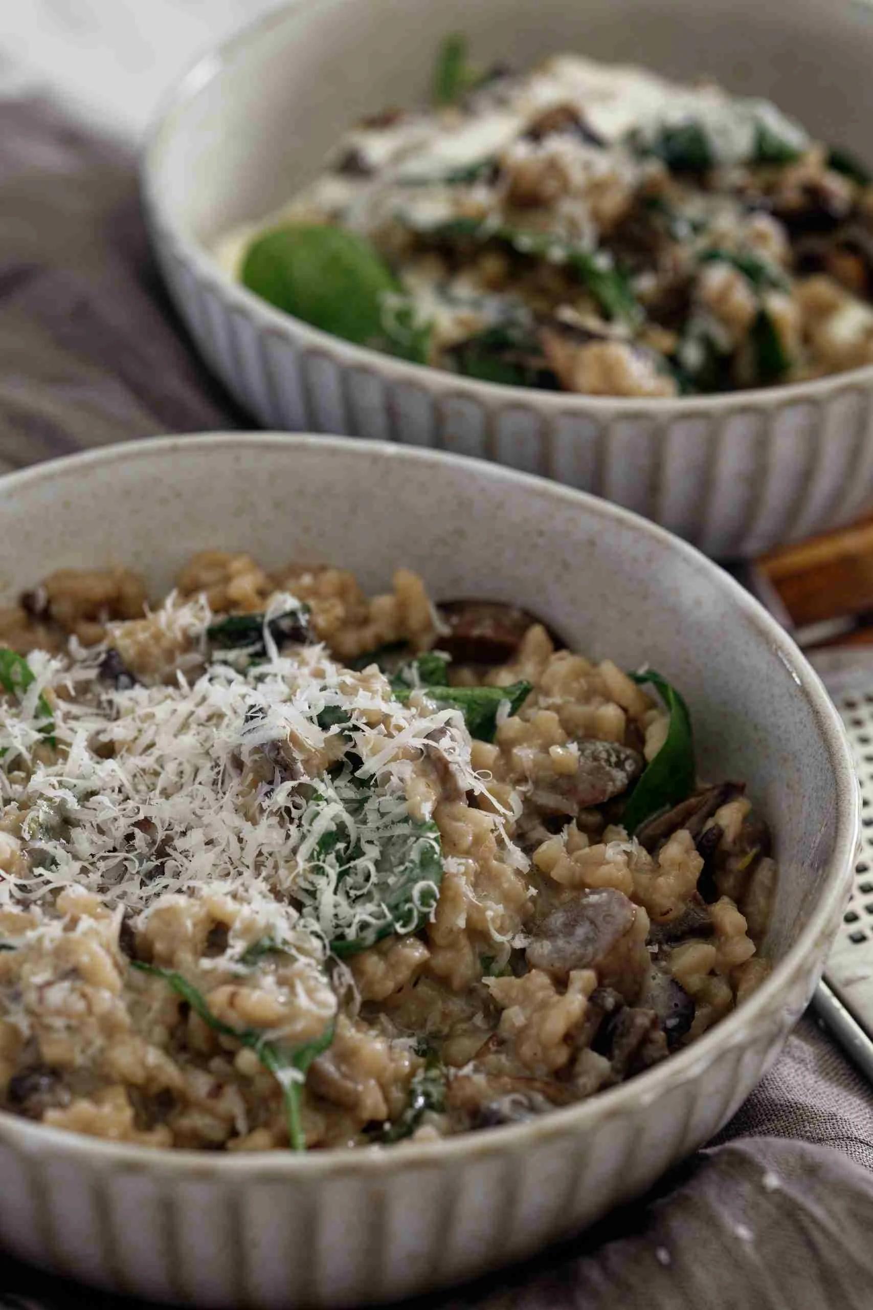 Close-up shot of creamy spinach and mushroom risotto in a shallow bowl, garnished with parmesan cheese