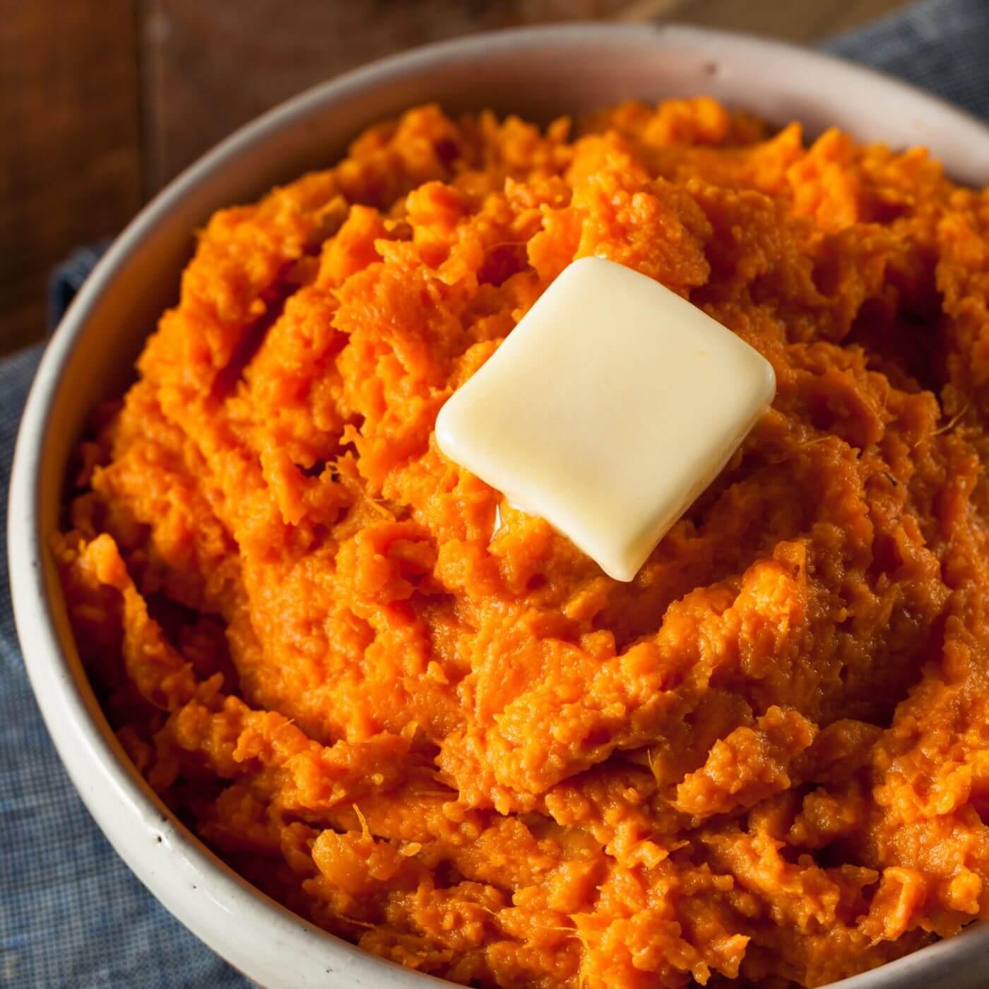 Grandma's hands mashing sweet potatoes in a rustic kitchen.
