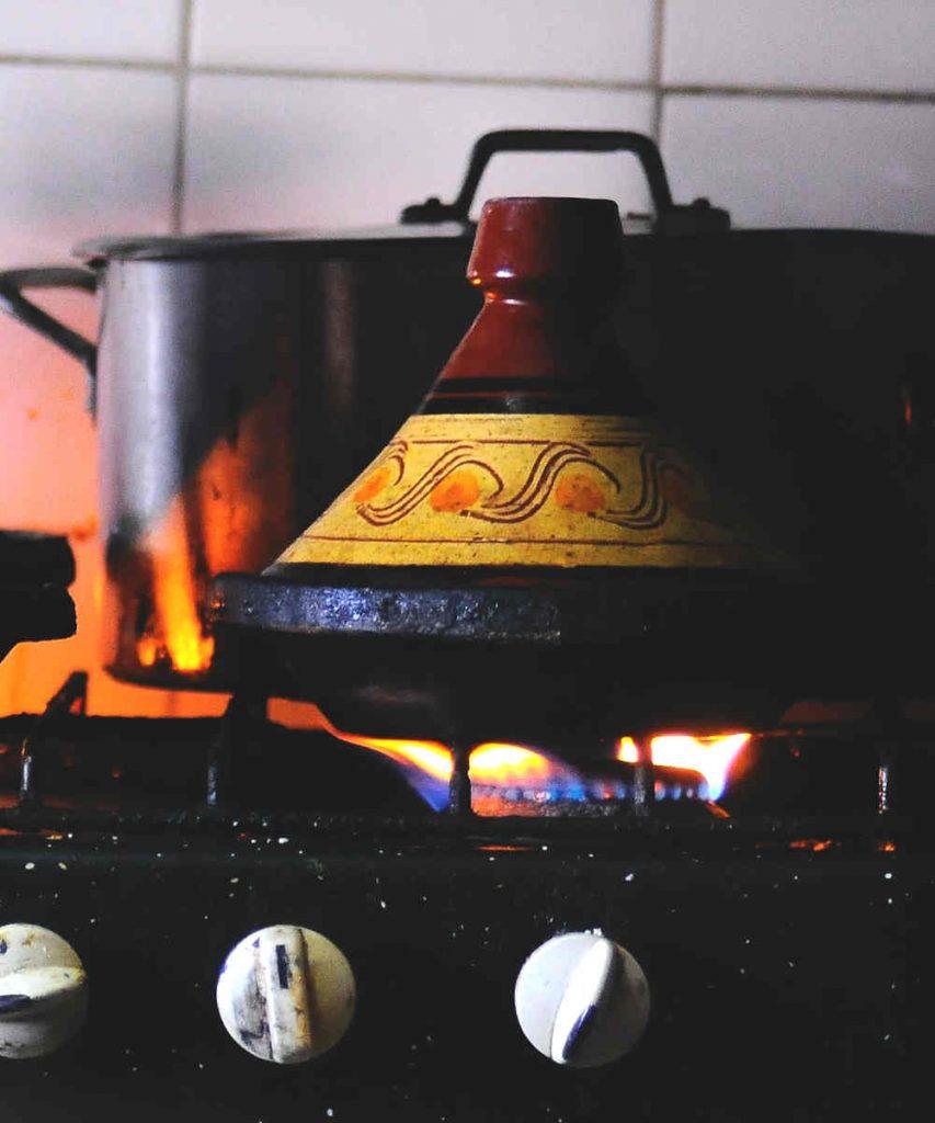 A tagine pot simmering on a stove, emitting steam