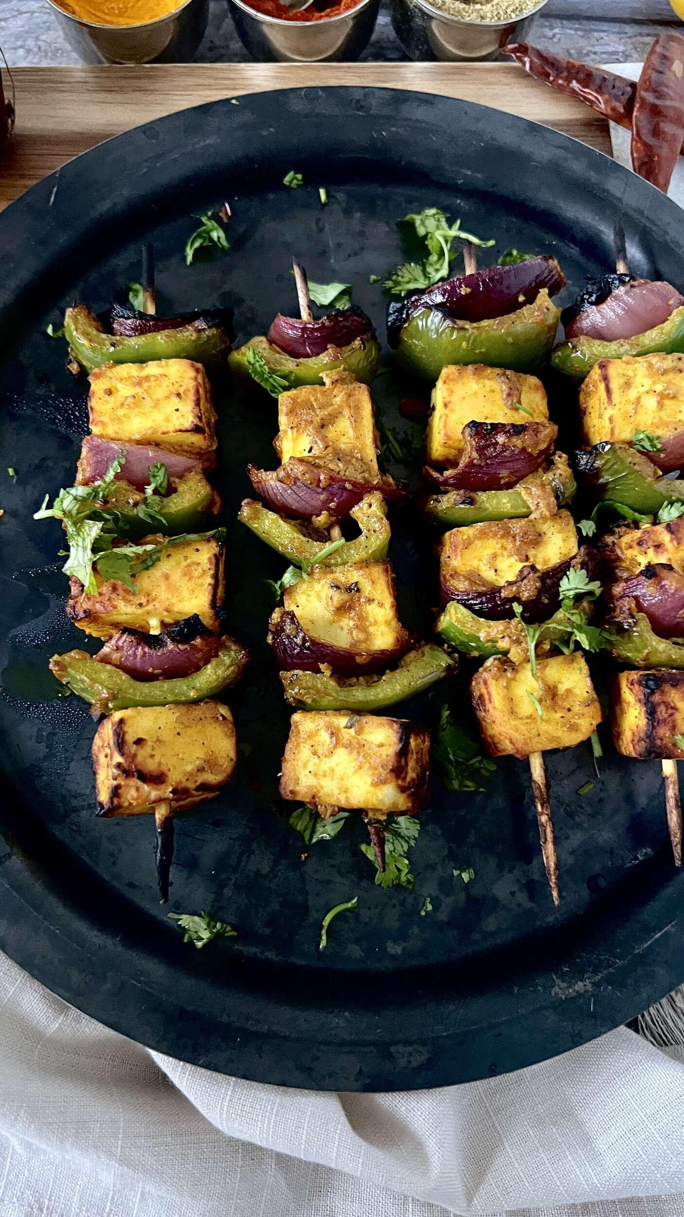 Grilled Five-Spice Paneer Tikka skewers served on a rustic wooden board