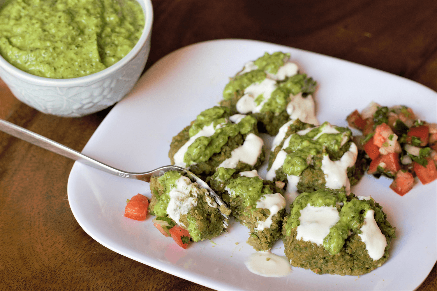 A person enjoying a plate of falafel with avocado crema