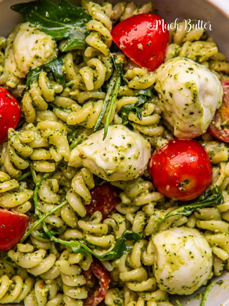 A vibrant photo of wholesome wheat pasta tossed with vibrant green pesto and juicy cherry tomatoes.