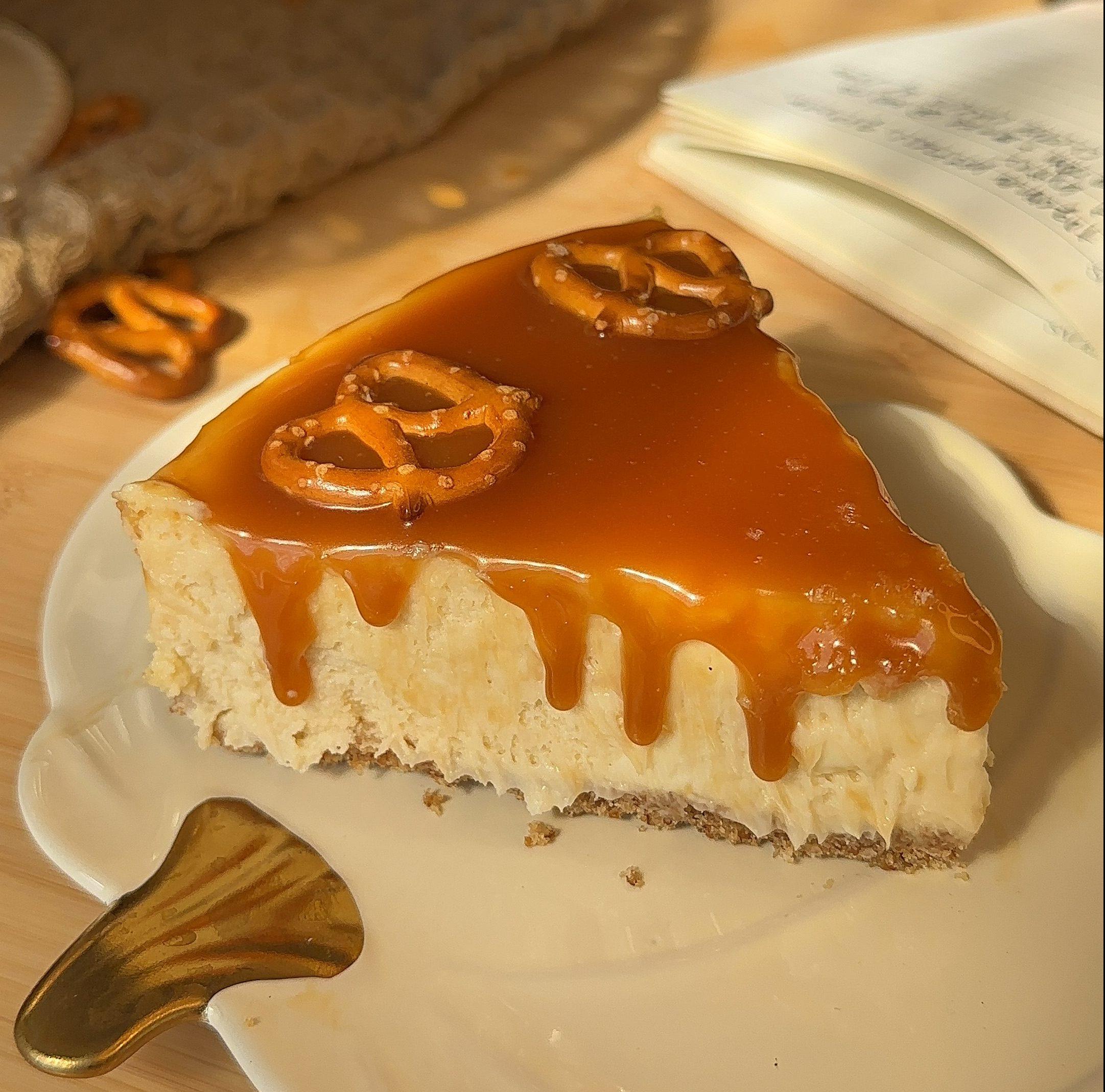 A slice of salted caramel pretzel cheesecake with pretzels and caramel drizzle on top