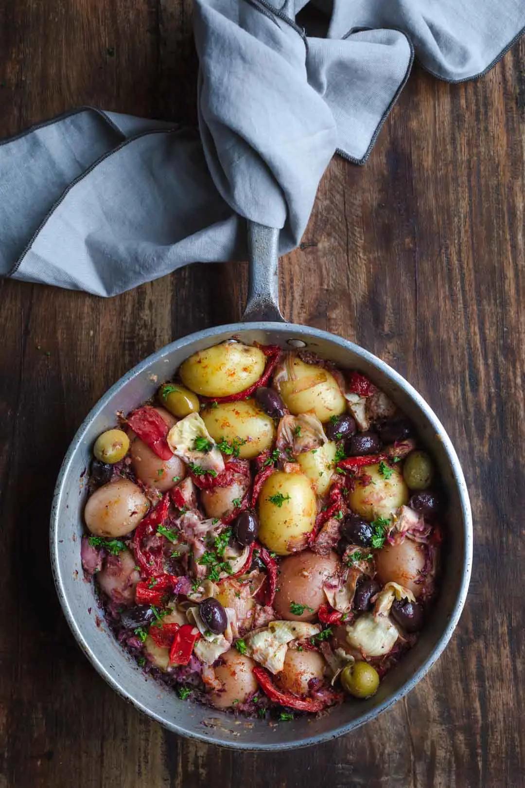 A rustic wooden table set with a bowl of Boiled Potatoes with Roasted Red Peppers and Feta
