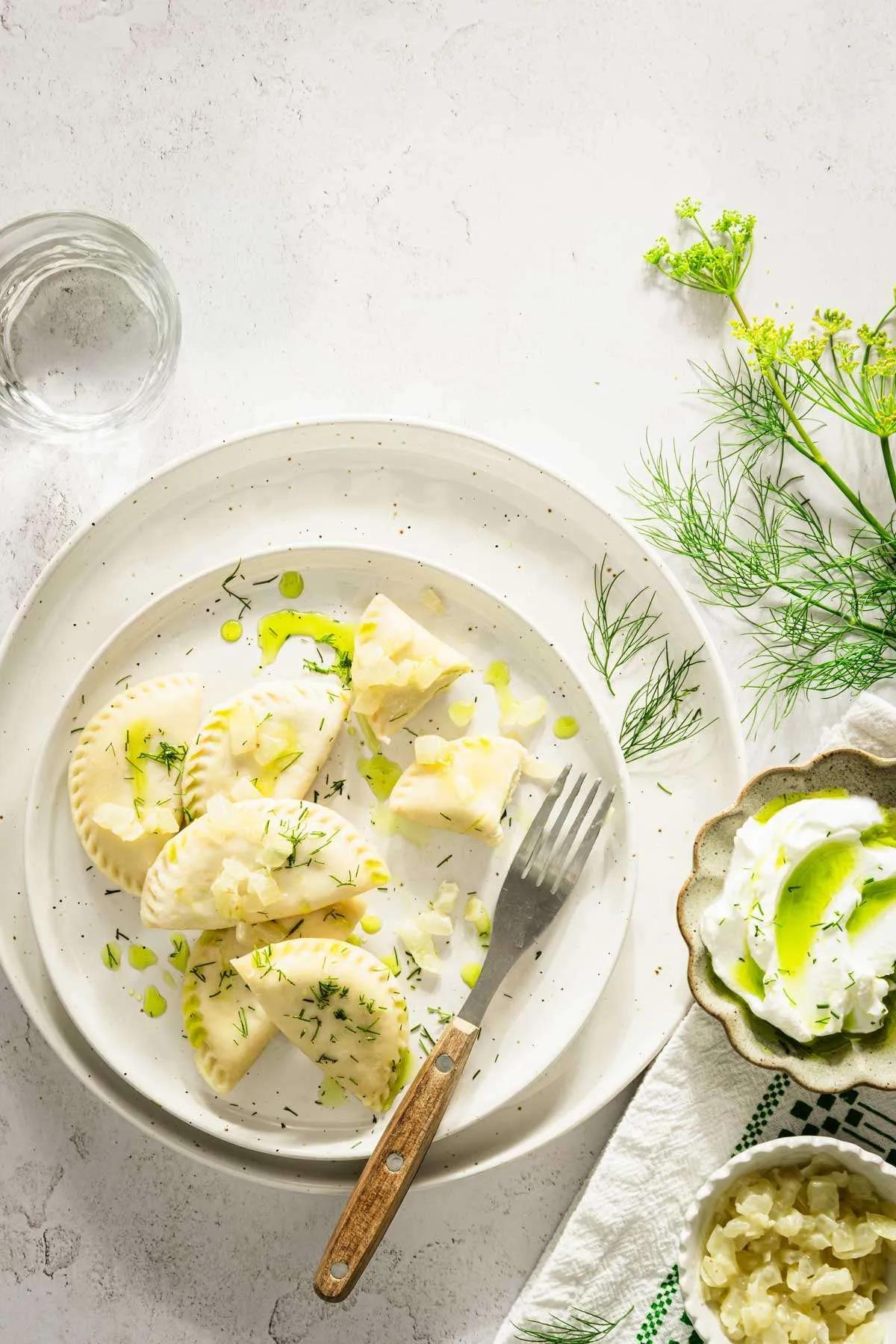 A plate of Polish Pierogi Croissants served with a dollop of sour cream and a sprinkle of fresh dill, styled for a brunch setting.