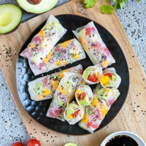 plate of avocado and black bean spring rolls with lime wedges
