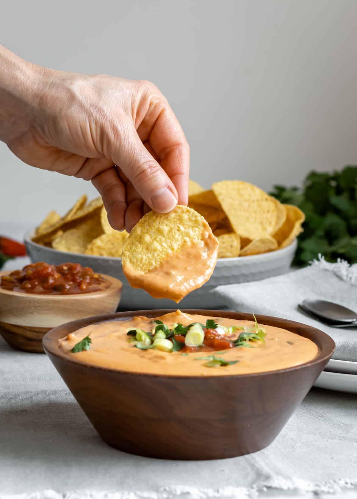 cashew queso dip being scooped with a tortilla chip
