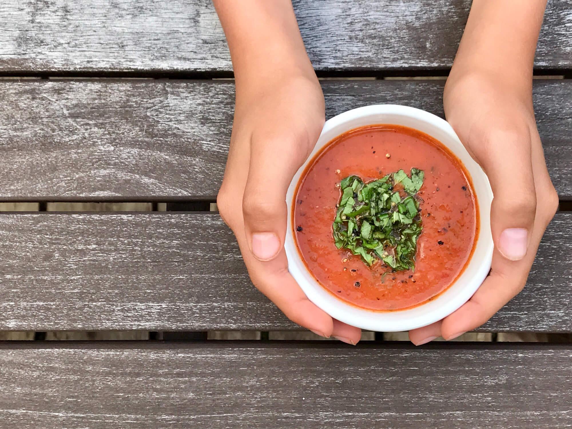 A person enjoying a bowl of creamy tomato soup