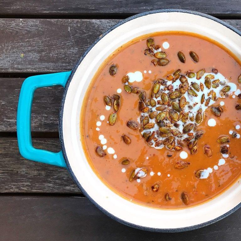 Close-up of a bowl of Spiced Pumpkin Soup with Toasted Pepitas, steam rising