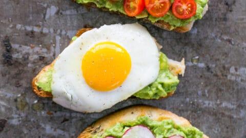 person preparing an open-faced avocado and egg sandwich in a bright kitchen