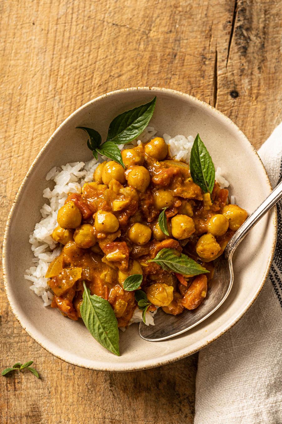 A vibrant and appetizing bowl of chickpea curry topped with toasted coconut flakes, served with rice or naan bread.