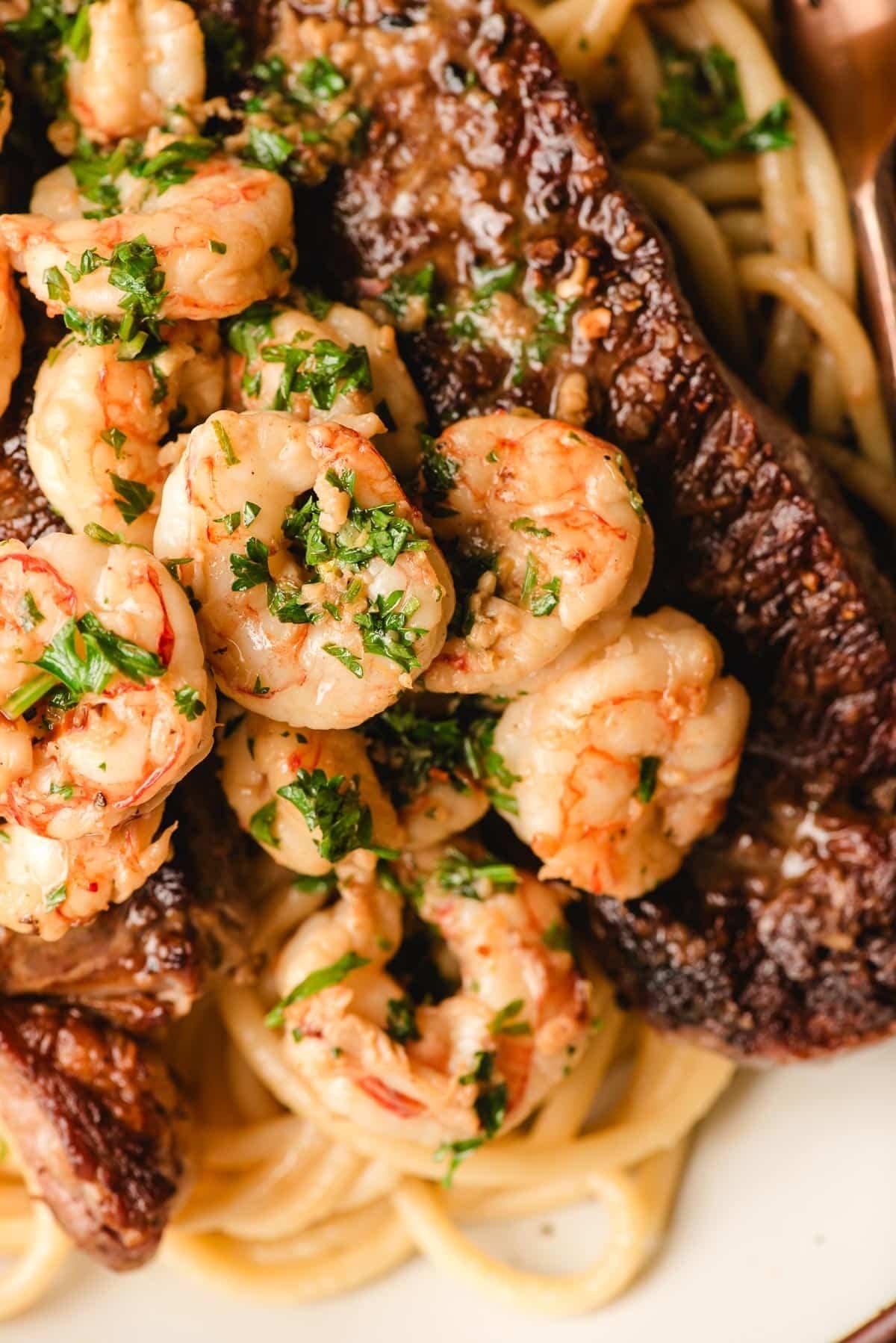 Close-up shot of sizzling steak and shrimp scampi in a skillet