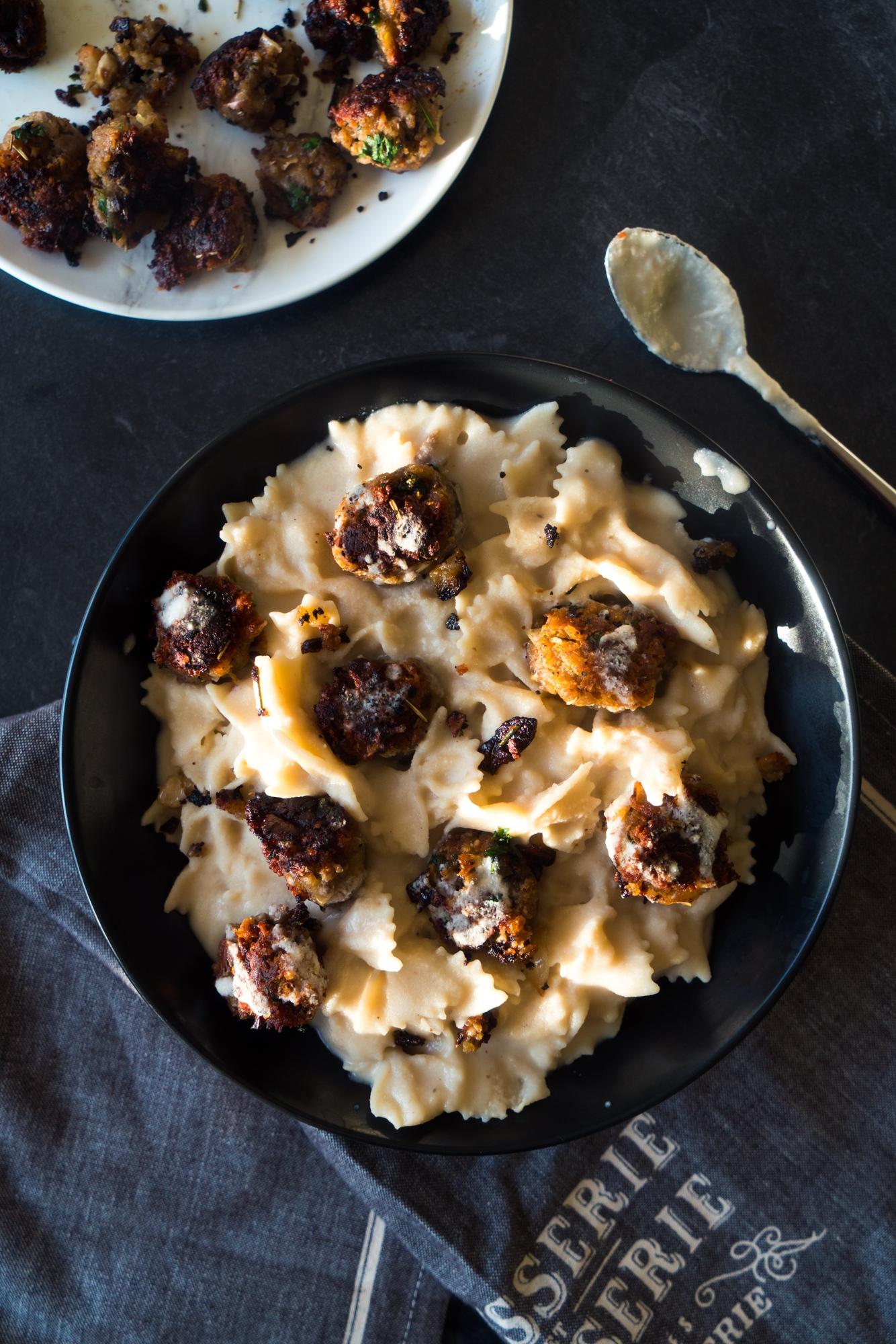 A person happily eating a bowl of plant-based meatballs and creamy alfredo sauce