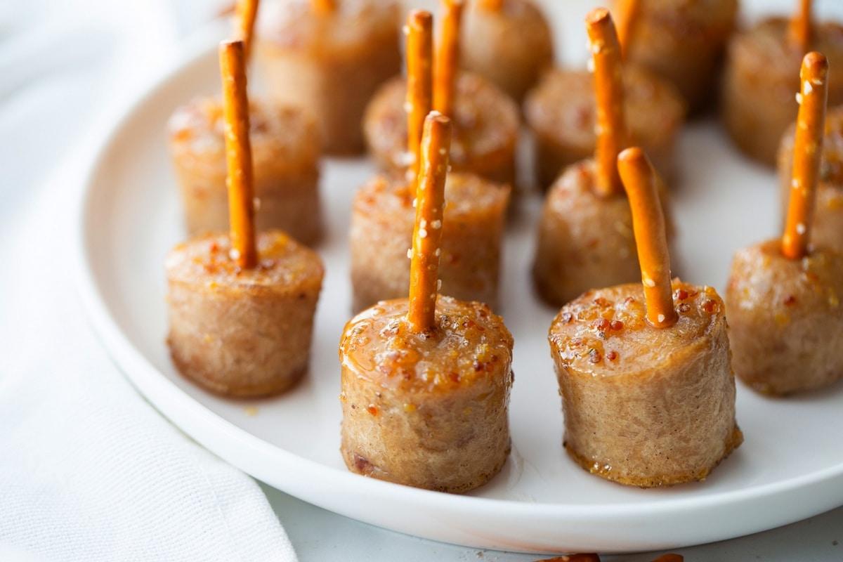 plate of golden brown maple heat glazed sausage balls on a rustic wooden board, garnished with chives
